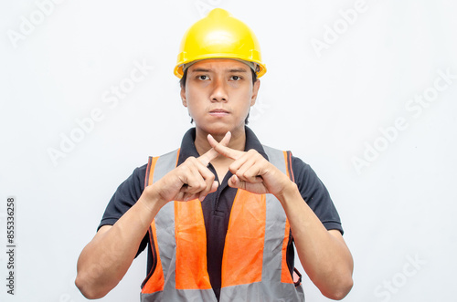 Asian male construction worker in a safety helmet and orang vest doing protest, rejecting and refusing something. labour day concept. 