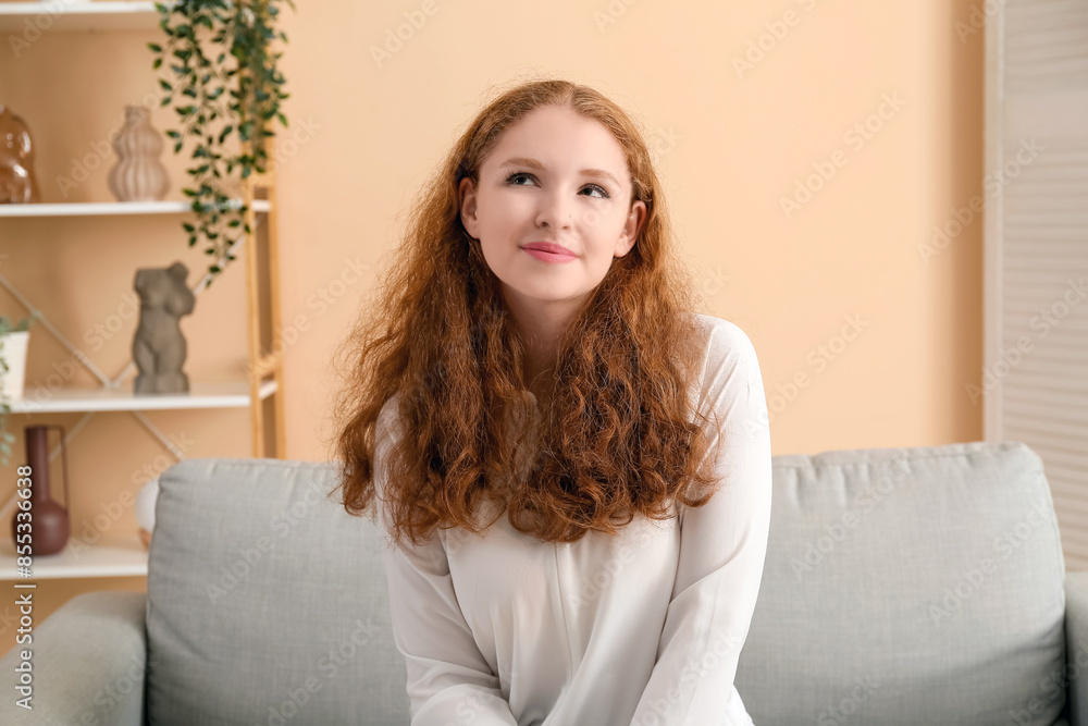 Naklejka premium Portrait of thoughtful redhead woman in living room