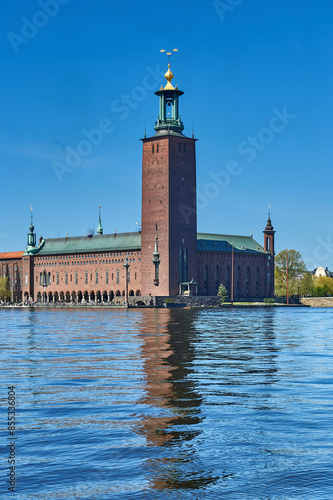 Stockholm City Hall with its red brick facade and tower on Kungsholmen Island, and Lake Malar with Riddarfjärden Bay or Gulf of Knights in the foreground photo