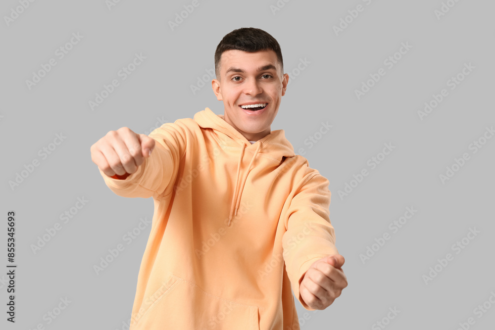 Young man with imaginary steering wheel on grey background