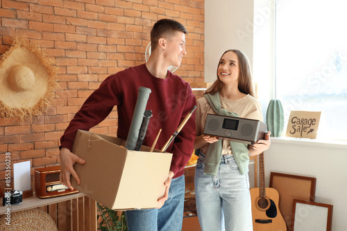 Fotografia Young couple with box of unwanted stuff in room. Yard Sale