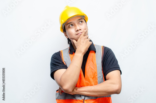 Title	
young asian man construction worker using yellow helmet and orange vest makes a thinking gesture. asian male worker in pensive expression while thinking looking for idea.