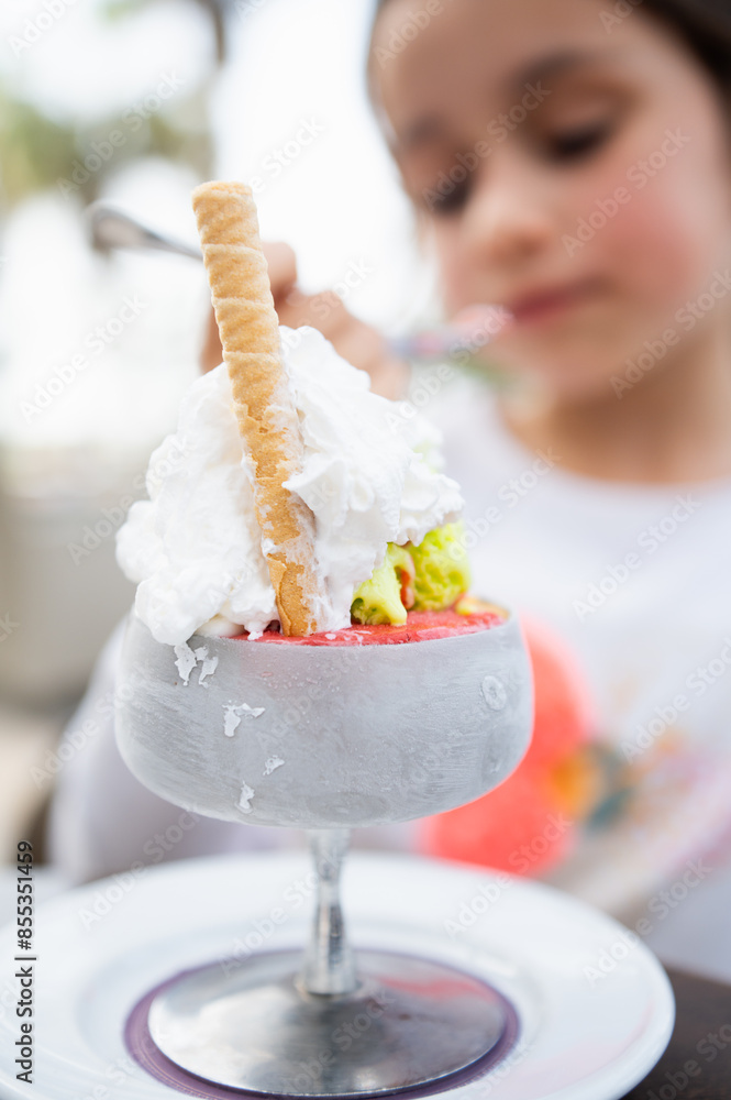 Child enjoying a delicious ice cream sundae with whipped cream Child enjoying a delicious ice cream sundae with whipped cream