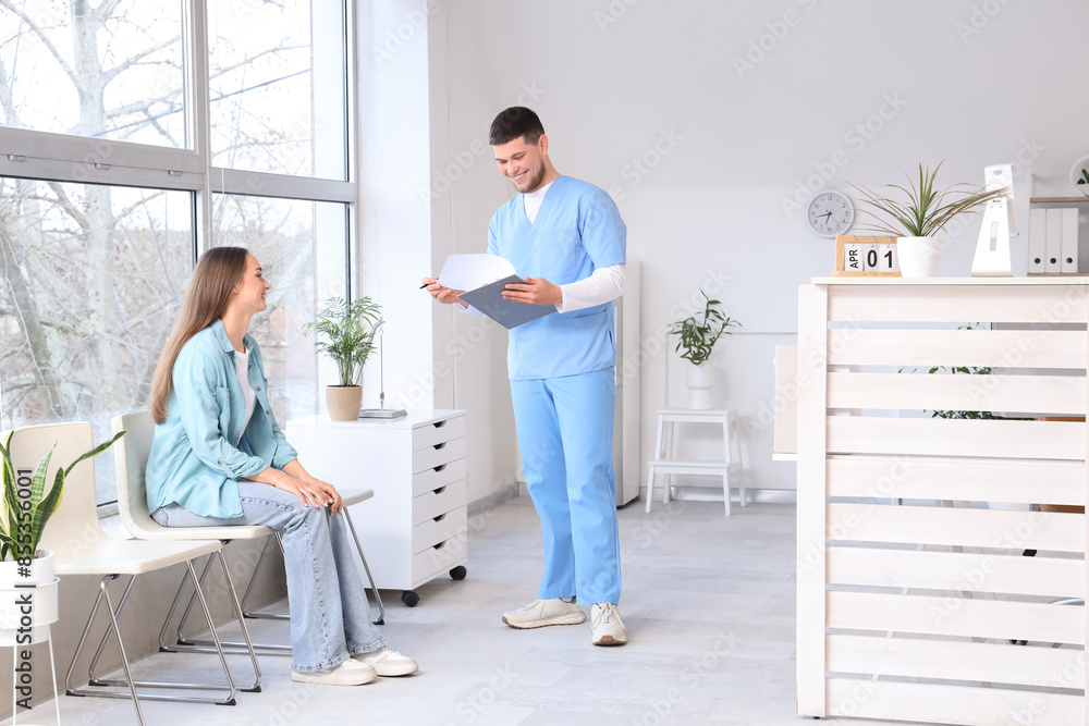 Male receptionist with waiting patient in clinic Male receptionist with waiting patient in clinic