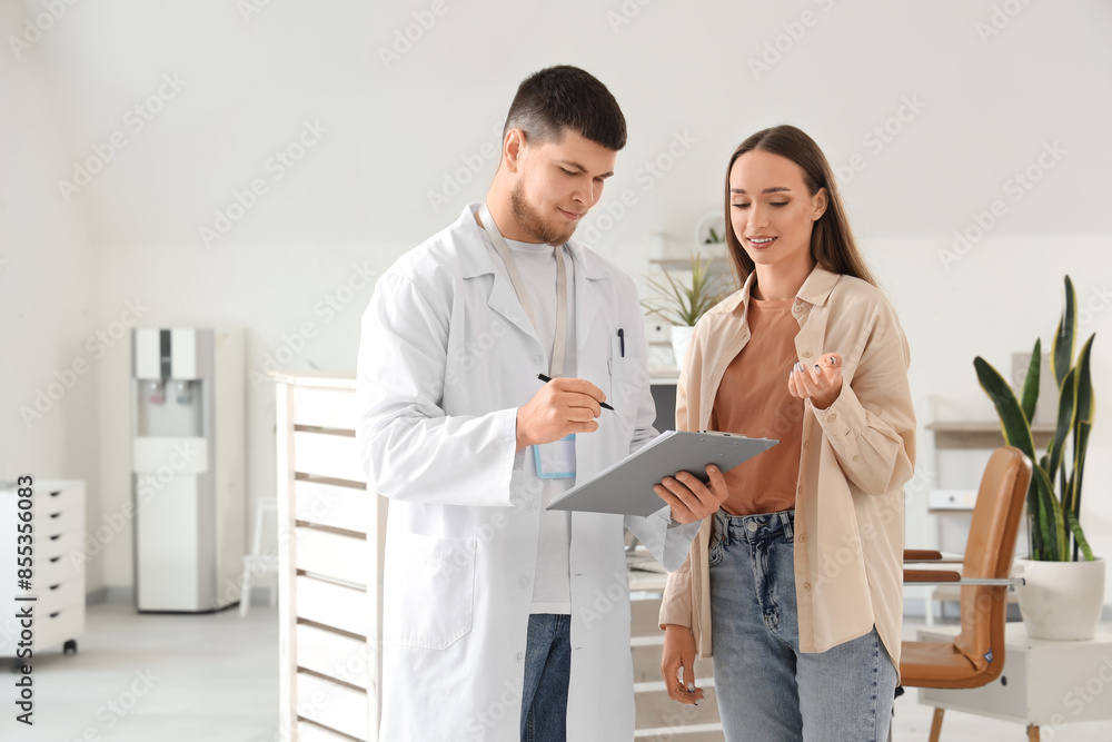 Obraz premium Male receptionist with clipboard and patient in clinic