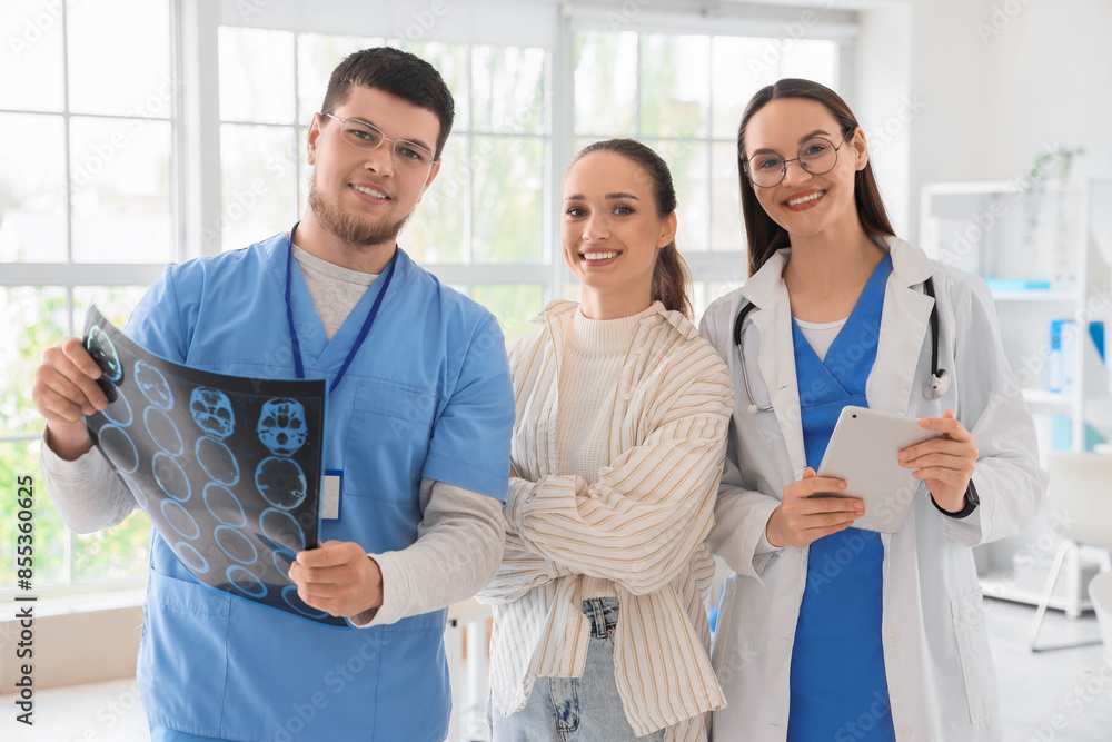 Obraz premium Smiling doctors with MRI scan and patient in clinic