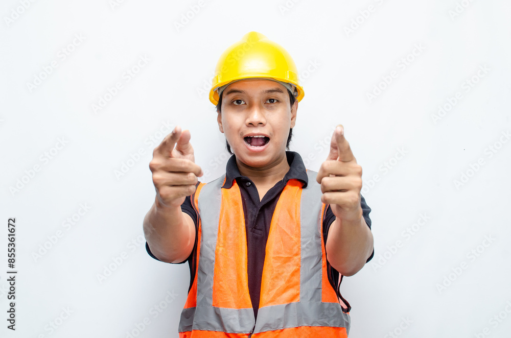 asian man consrtruction worker wearing yellow safety helmet and orange vest smiling and pointing finger to copy space with happy and surprised expression. asian man consrtruction worker wearing yellow safety helmet and orange vest smiling and pointing finger to copy space with happy and surprised expression.