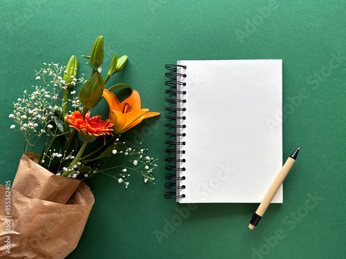 Open Notebook with Pen and Flowers on Green Background - Creative Workspace Essentials. photo