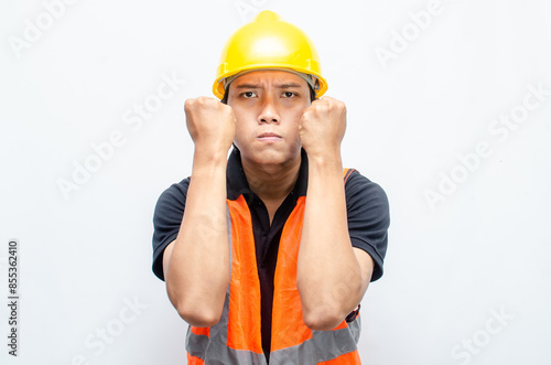 stressed overworked concept illustrated by asian male construction worker in orange vest and yellow safety helmet with furious, mad, sad, angry expression. 