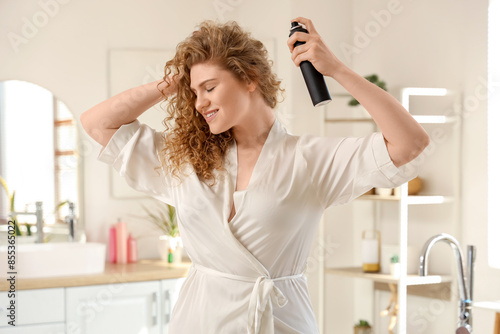 Fotografía Young woman applying dry shampoo on her hair in bathroom
