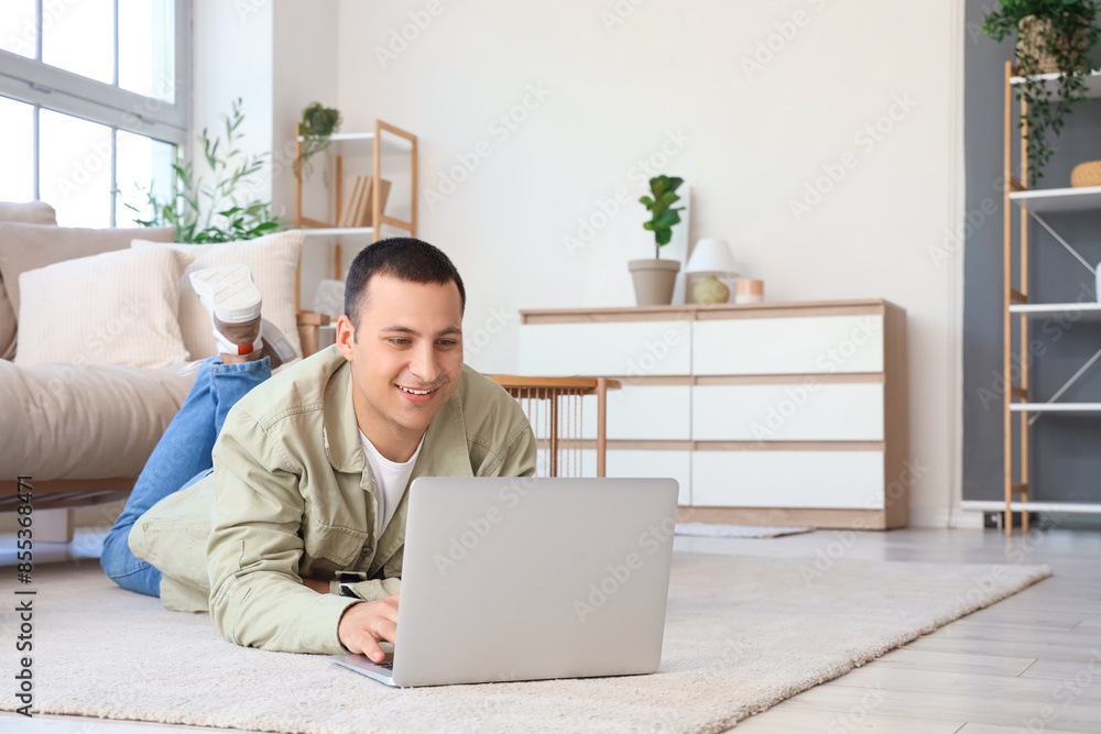 Young man using laptop on soft carpet at home Young man using laptop on soft carpet at home