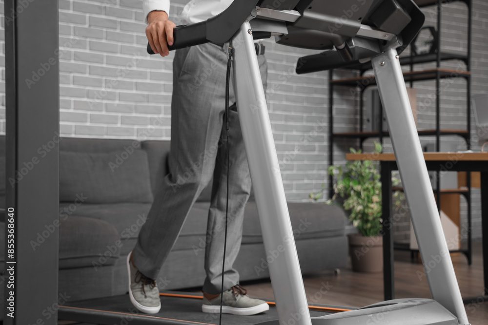 Young businessman training on treadmill in office Young businessman training on treadmill in office