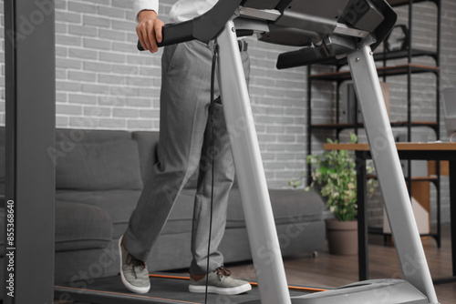 Young businessman training on treadmill in office