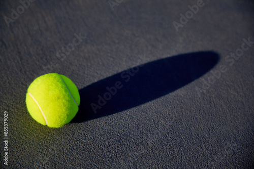A tennis ball on tennis court with court lines and shadows