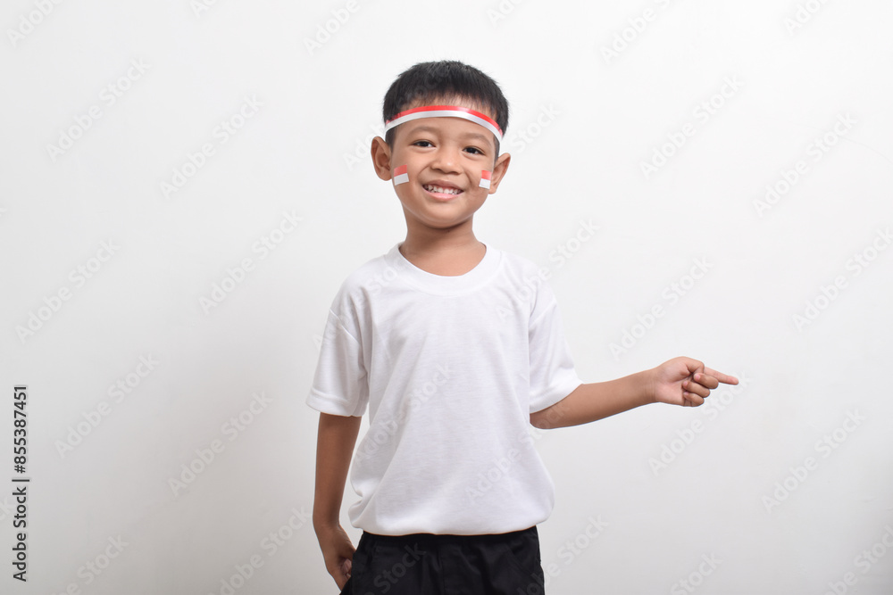 Cute little Asian boy wearing flag headband pointing at the copy space beside himi solated on white background. Concept of Indonesia's independence day on August 17 Cute little Asian boy wearing flag headband pointing at the copy space beside himi solated on white background. Concept of Indonesia's independence day on August 17
