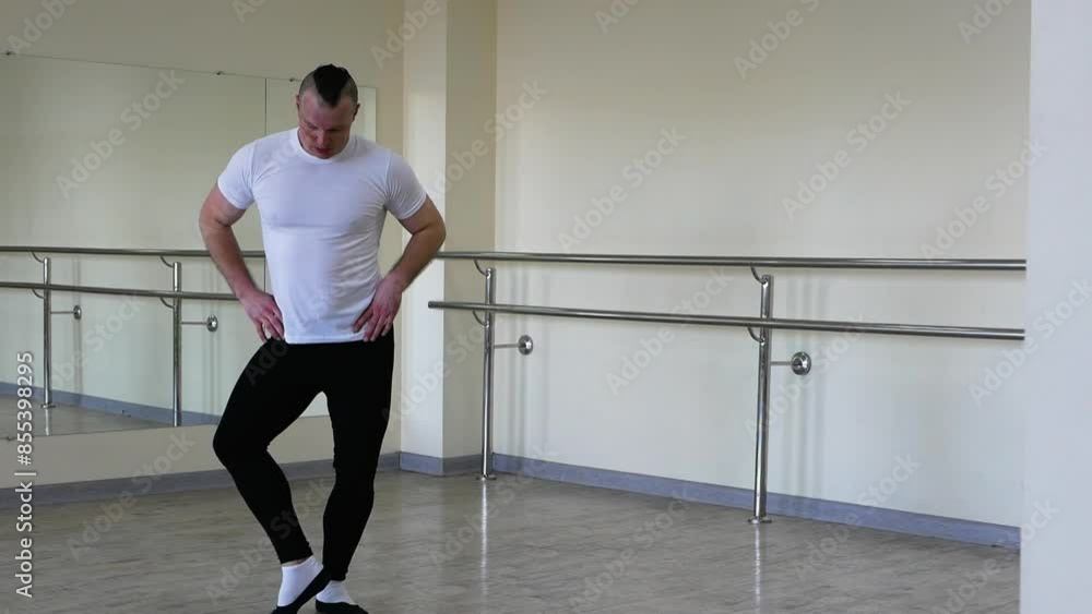A ballerina dancer warms up on a ballet barre. A man in ballet shoes is rehearsing in the hall. Professional classical ballet, warming up during training A ballerina dancer warms up on a ballet barre. A man in ballet shoes is rehearsing in the hall. Professional classical ballet, warming up during training
