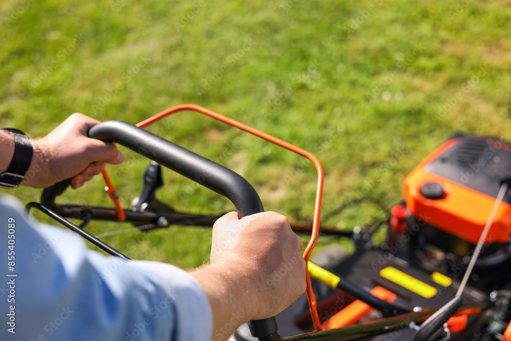 Man cutting grass with lawn mower outdoors, closeup Man cutting grass with lawn mower outdoors, closeup