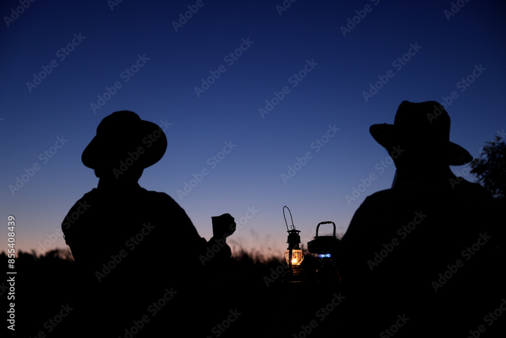 Obraz premium 夕暮れのキャンプを楽しむシルエットの男性二人