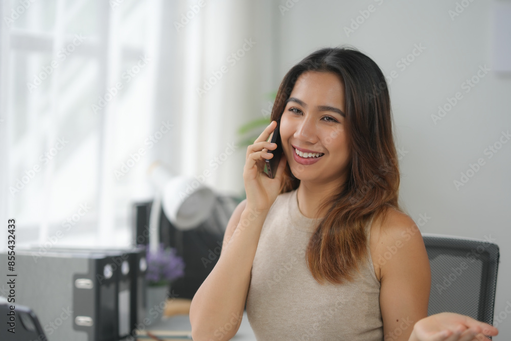 Smiling professional woman chatting on her phone at her desk in a modern office setting, embracing casual work atmosphere and productivity. Smiling professional woman chatting on her phone at her desk in a modern office setting, embracing casual work atmosphere and productivity.