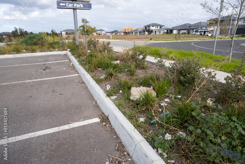 Bilde på lerret An empty neglected public parking lot in a suburban street has litter trash scattered around, and unkempt vegetation with weeds