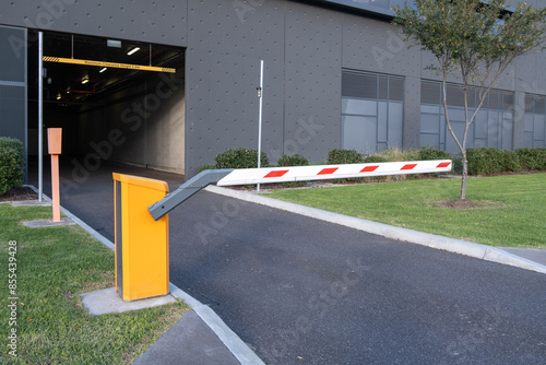 At the entrance of an indoor parking garage, a closed automatic barrier arm or a boom gate operator controls access and traffic flow.This system ensures only authorized vehicles can enter for security photo