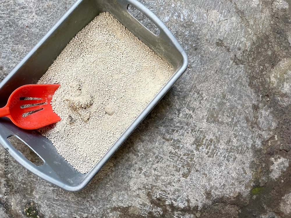 Clump the cat feces in the litter box with an orange scoop Clump the cat feces in the litter box with an orange scoop