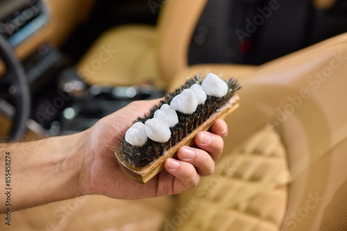 Detailed closeup image showing hands applying shoe cleaner to a brush for precise cleaning purposes