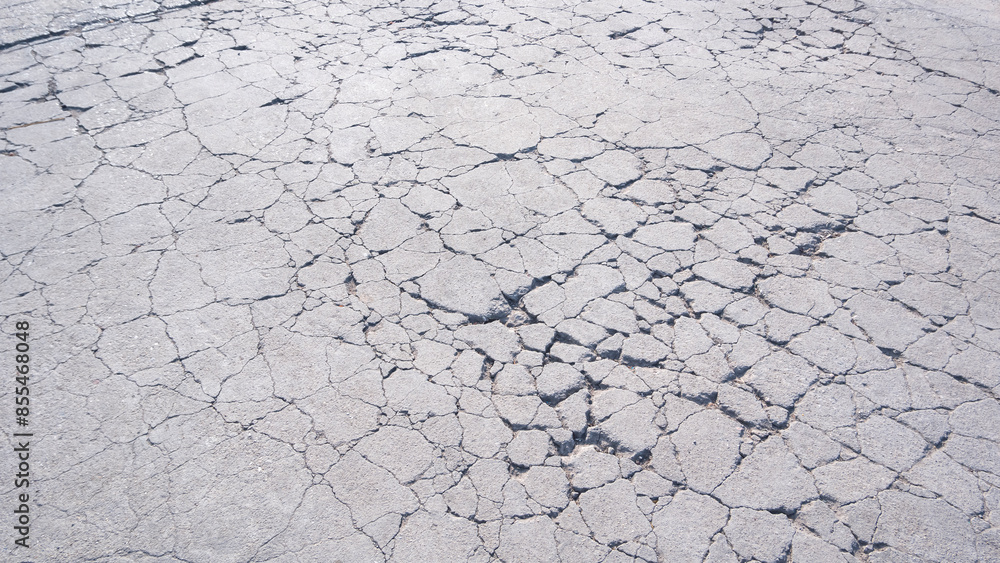 The old badly damaged concrete yard floor in car park area with many broken crack lines texture on surface The old badly damaged concrete yard floor in car park area with many broken crack lines texture on surface