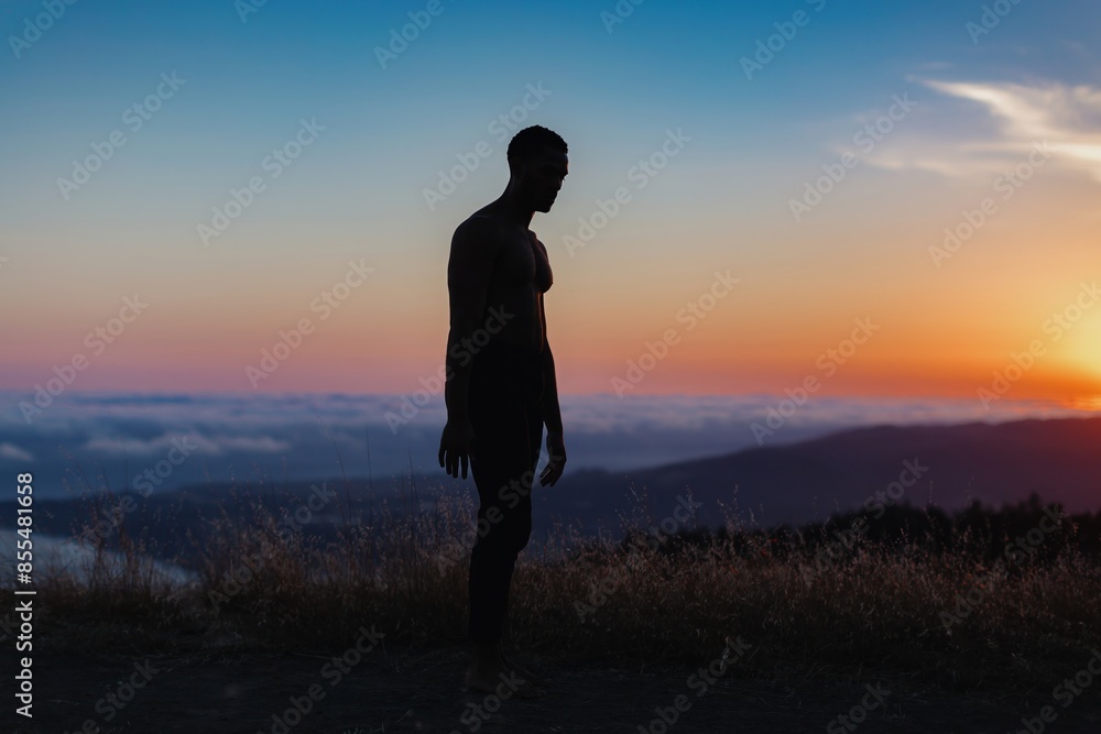 Silhouette of male ballet dancer standing in a pose. Behind him are heavenly clouds and the sun is setting. Silhouette of male ballet dancer standing in a pose. Behind him are heavenly clouds and the sun is setting.