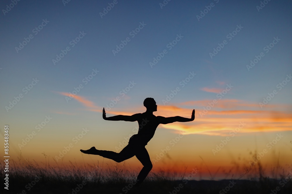 Silhouette of male ballet dancer doing a majestic dance move in nature, Behind him are heavenly clouds and the sun is setting. Silhouette of male ballet dancer doing a majestic dance move in nature, Behind him are heavenly clouds and the sun is setting.