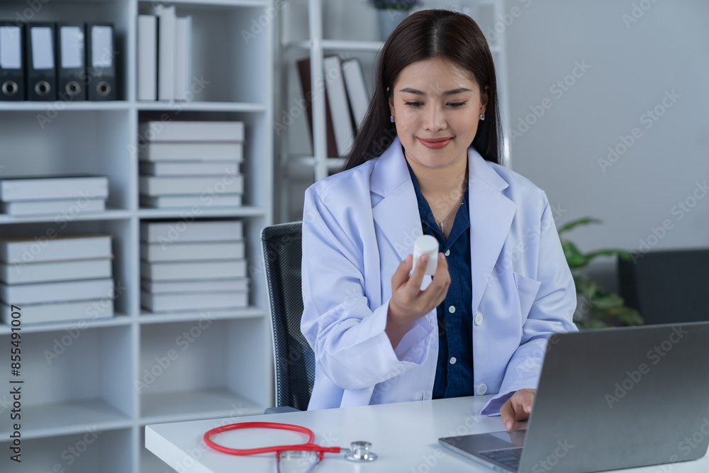 A photograph of a female doctor sitting at her desk in an office. A photograph of a female doctor sitting at her desk in an office.