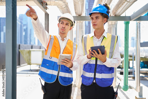 Technicians checking sewer pipes and water tank area at urban industrial site