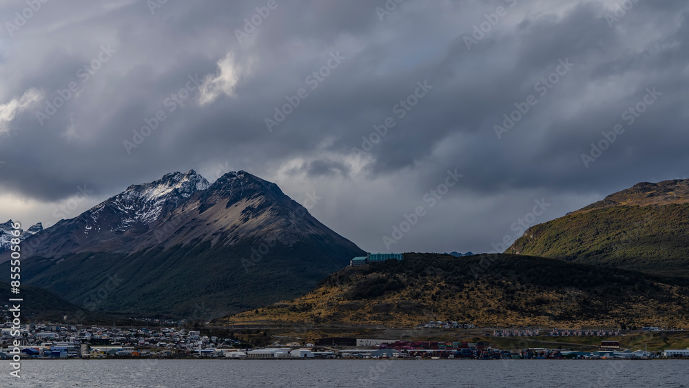 Beautiful snow-capped Andes mountains against a cloudy sky. The hotel building is on a hill. The town houses of Ushuaia are at the foot, on the banks of the Beagle Canal. Argentina. Tierra del Fuego Beautiful snow-capped Andes mountains against a cloudy sky. The hotel building is on a hill. The town houses of Ushuaia are at the foot, on the banks of the Beagle Canal. Argentina. Tierra del Fuego