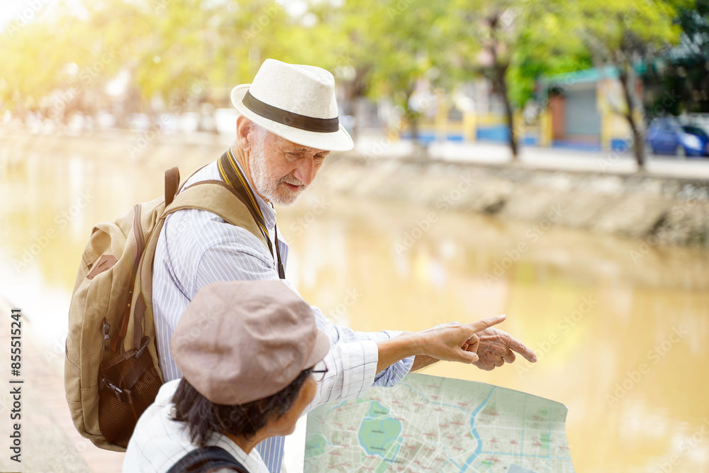 Closeup American senior tourist man with his tour guide are looking at city maps to find tourist attractions on blurred of city with sun bright background. Senior tourist concept Closeup American senior tourist man with his tour guide are looking at city maps to find tourist attractions on blurred of city with sun bright background. Senior tourist concept