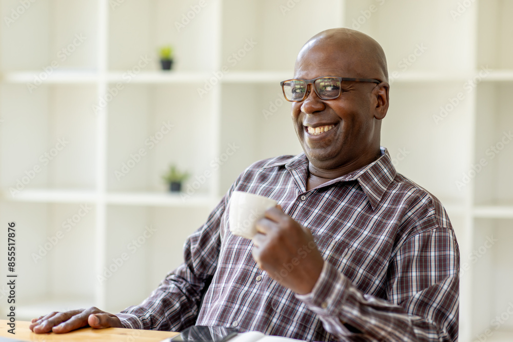 Portrait of happy smiling senior man sitting on desk at cafe using smartphone and laptop Portrait of happy smiling senior man sitting on desk at cafe using smartphone and laptop