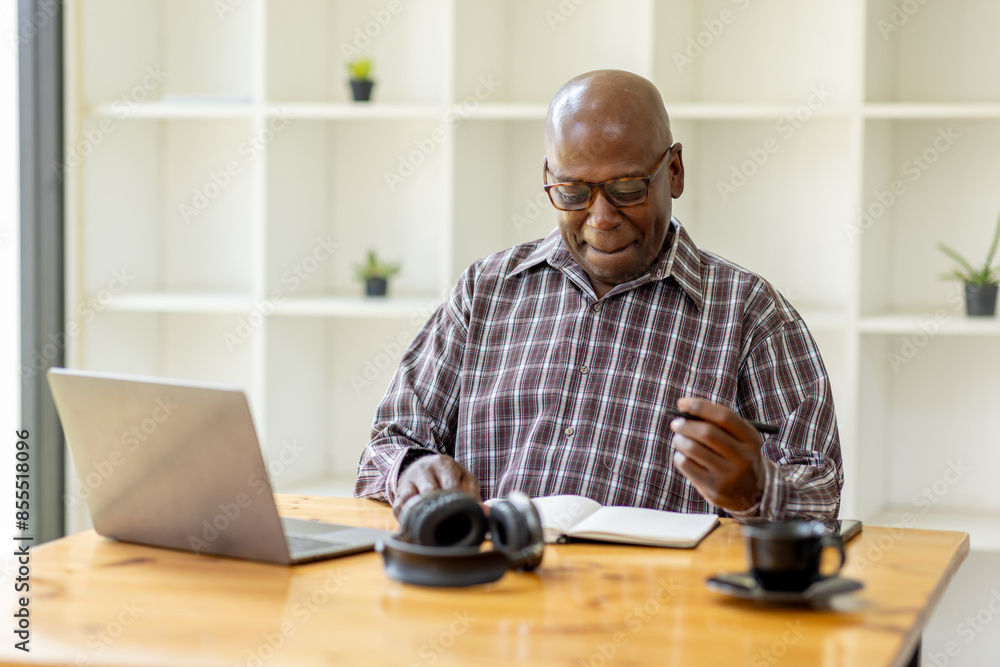 Portrait of happy smiling senior man sitting on desk at cafe using smartphone and laptop Portrait of happy smiling senior man sitting on desk at cafe using smartphone and laptop