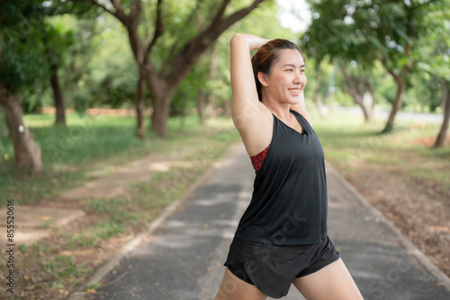 Asian woman stretching her muscles before exercising at the park. Runner stretching her muscles after running. Health and body shape concept.