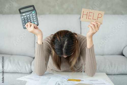 Bilde på lerret Stressed and headache asian woman with large bills or invoices no money to pay to expenses and credit card debt