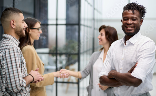 young black man smiling in front of his colleagues © Katsiaryna