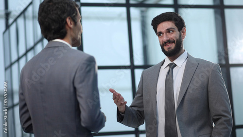 two businessmen discuss the document standing in the office lobby.