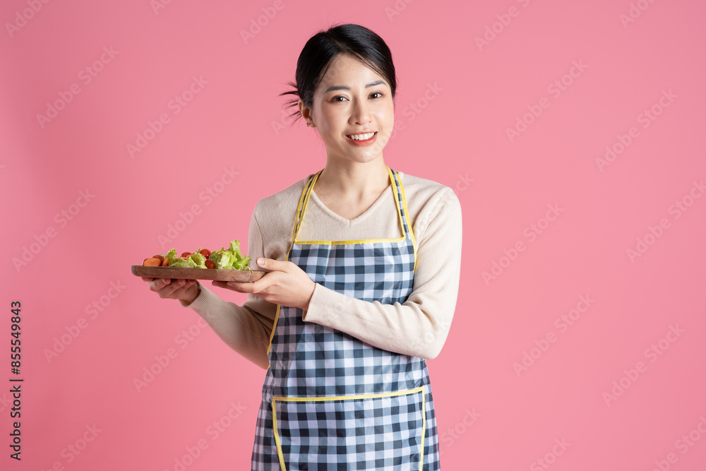 Portrait of woman wearing apron, posing on pink background Portrait of woman wearing apron, posing on pink background