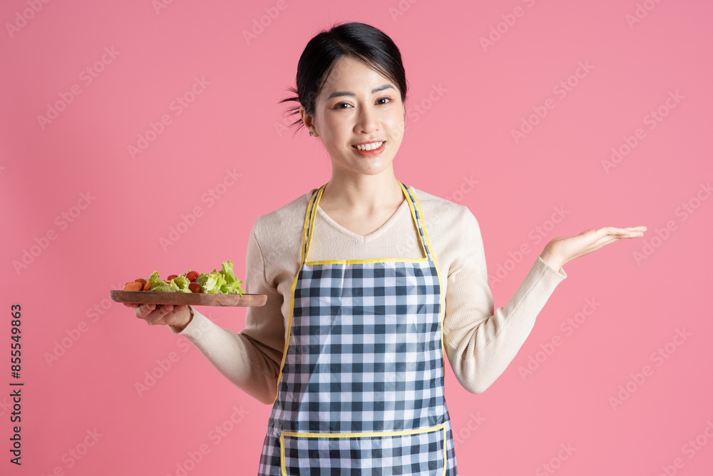 Portrait of woman wearing apron, posing on pink background Portrait of woman wearing apron, posing on pink background