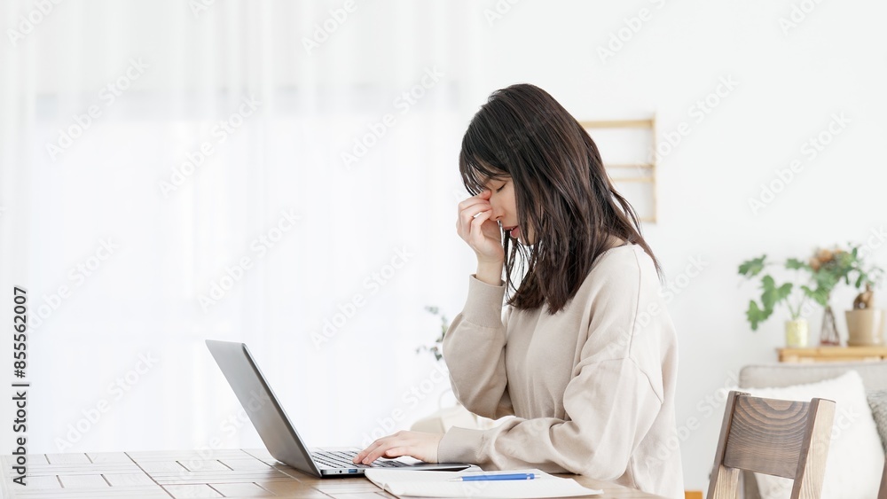 パソコン作業に目の疲れを感じる女性 パソコン作業に目の疲れを感じる女性