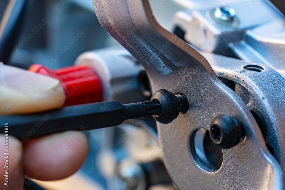 A man unscrews the bolt with a hex wrench for adjusting the miter saw, closeup. Worker with allen screw with his wrench A man unscrews the bolt with a hex wrench for adjusting the miter saw, closeup. Worker with allen screw with his wrench