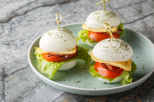 Obraz na płótnie Easter Egg Appetizer Skewers with cheese, bacon, tomato and lettuce close-up in a plate on the table. Horizontal w salonie