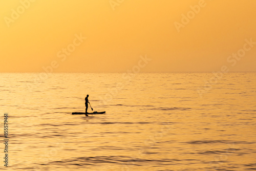 A man on his paddleboard in silhouette out in the Mediterranean Sea near Haifa, Israel during the golden hour with a beautiful orange sunset.   © Barbara