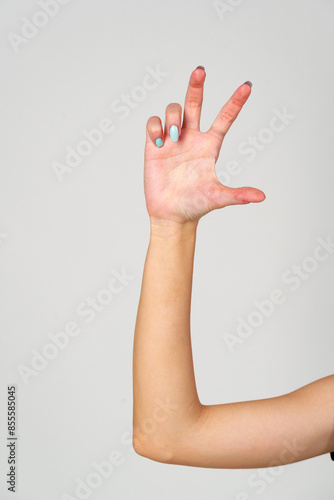 Womans Hand With Blue Nail Polish on gray background.