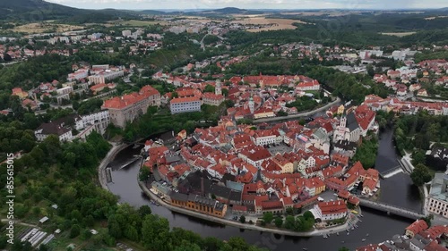 Český Krumlov, South Bohemia, Czechia, June 2023. Drone orbits with views of with Svornosti Square Church of St. Vitus Vltava river and lush green hills in background. photo