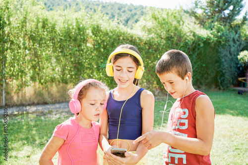 portrait of three boys together with headphones looking at a phone photo