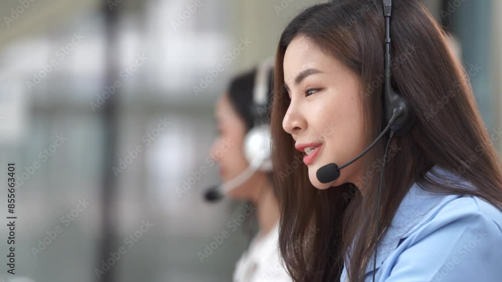 Happy smiling operator Asian woman customer service agent with headsets working on a computer in a call center.
